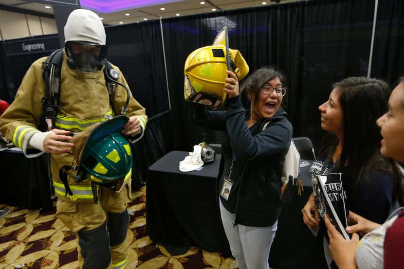 Xitlali Parra (center) from John Adams Middle School is excited to put on a fire helmet next...