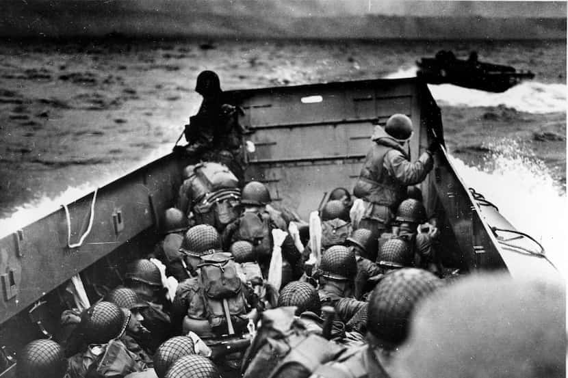 In this file photo, allied troops crouch behind the bulwarks of a landing craft as it nears...