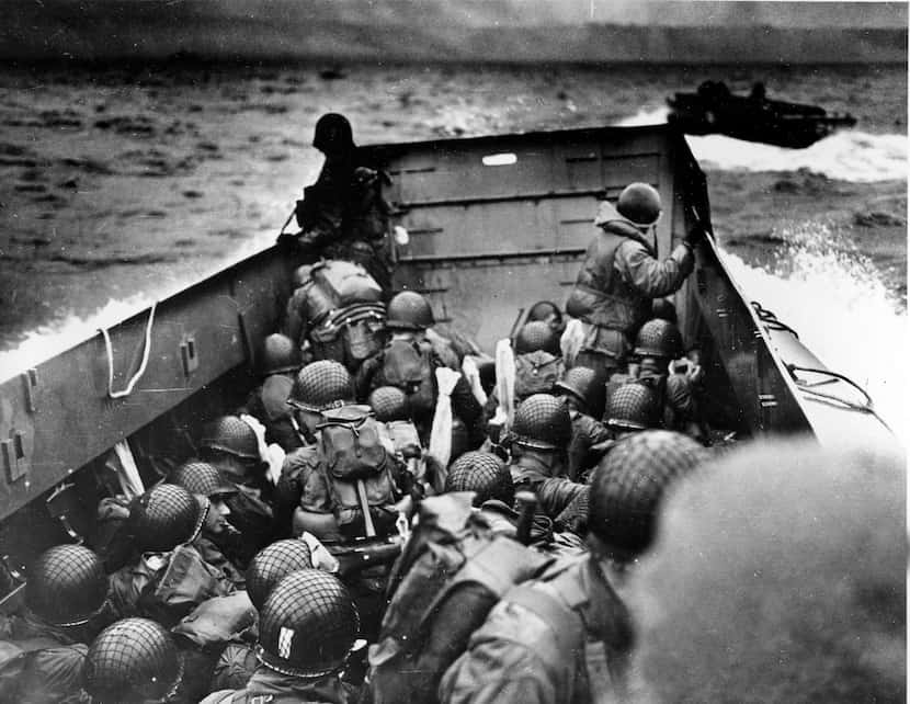 Allied troops crouch behind the bulwarks of a landing craft as it nears Omaha Beach during a...