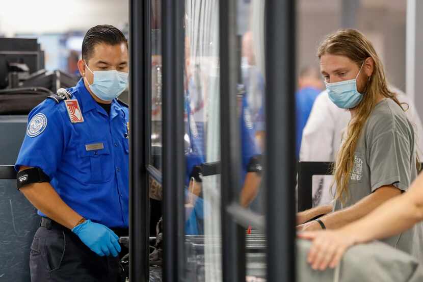 A TSA agent directs travelers at a security checkpoint at DFW International Airport.