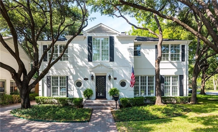 A 1940s home has green shutters and doors and a white exterior.