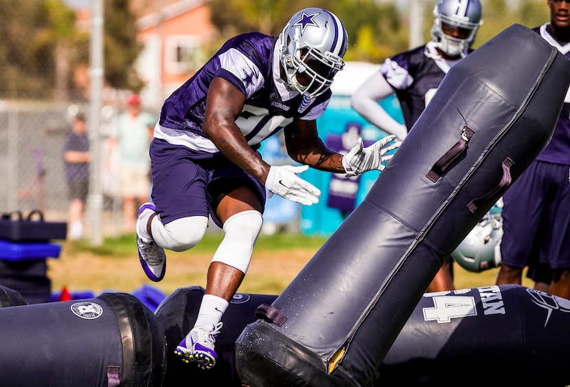 Dallas Cowboys defensive end Demarcus Lawrence pushes past a blocking dummy during afternoon...