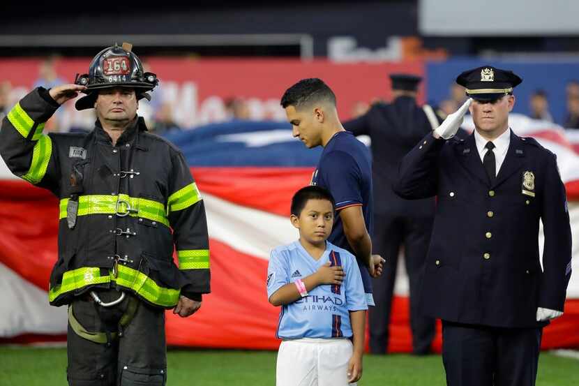 New York City FC's Tony Rocha, center, pauses as a firefighter, left, and police officer,...