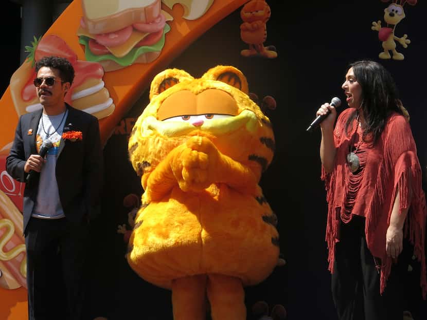 Un artista disfrazado como el personaje Garfield, centro, con los actores de doblaje...