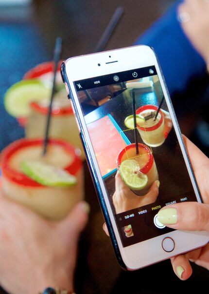 Stephanie Campos uses her phone to photograph her margarita at Urban Taco to share with her...