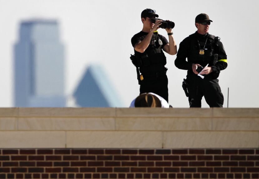 Law enforcement personnel kept their senses trained on the surrounding area from the roof of...