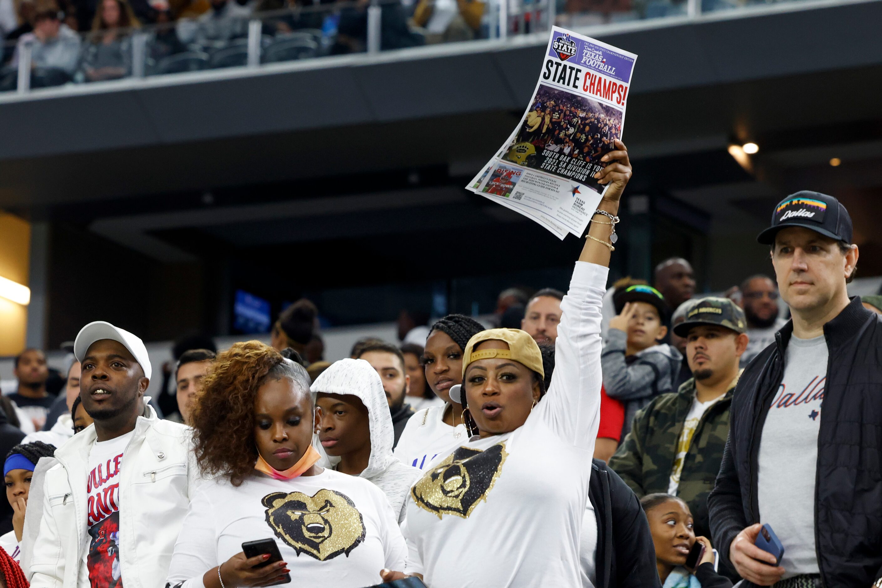 A South Oak Cliff fan raises a newspaper clipping proclaiming the team “state champs” after...