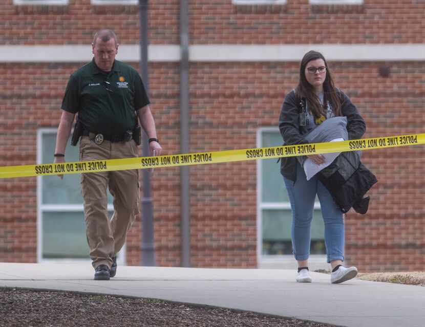 A resident is escorted out of the Pride Rock residence hall where two women were fatally...