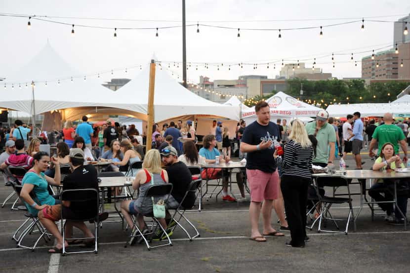 Attendants sit at tables and eat food from food trucks at Untapped Festival in Fort Worth,...