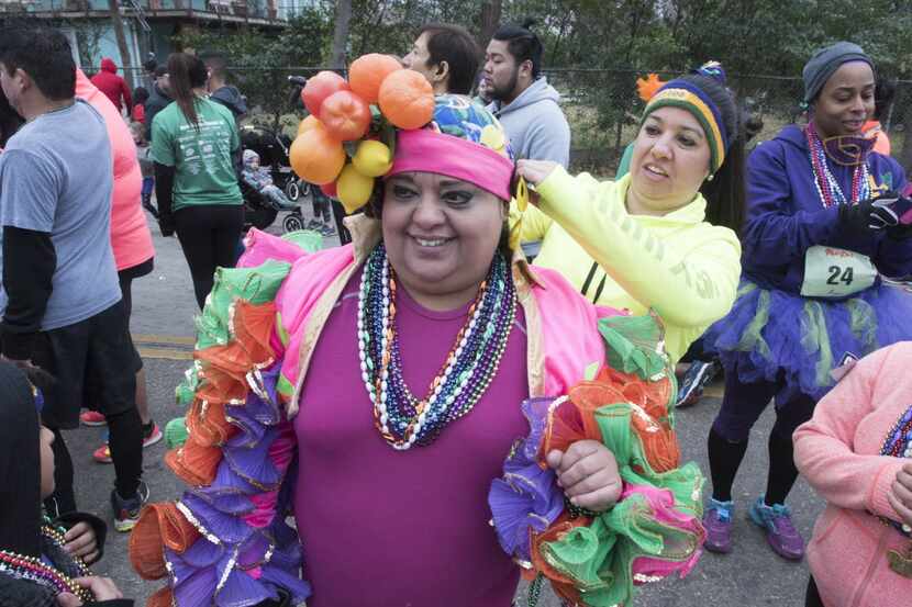 A runner dressed up as Carmen Miranda gets help with her costume before the start of the...