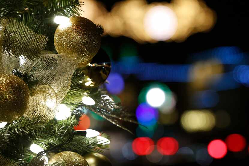 A decorated Christmas tree glows in front of a bevy of holiday lights as businesses in the...