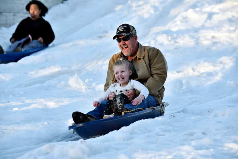 Rodney Allison and his granddaughter ride down the Frosty Snowhill at Six Flags.