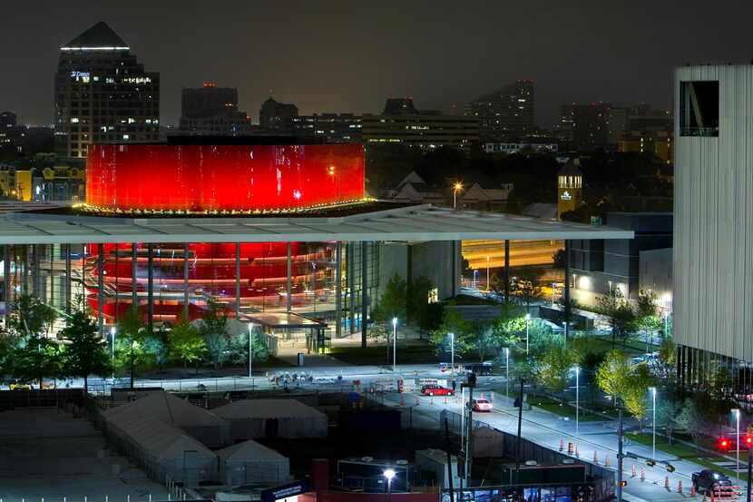 The red drum of the Winspear Opera House glows in the night with the Wyly Theatre to the right.