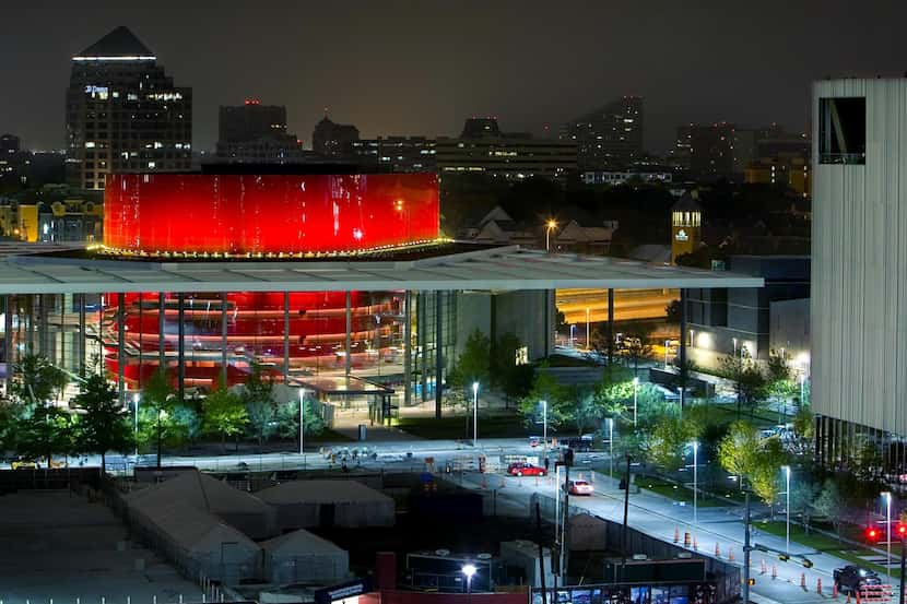 The red drum of the Winspear Opera House glows in the night with the Wyly Theatre to the right.