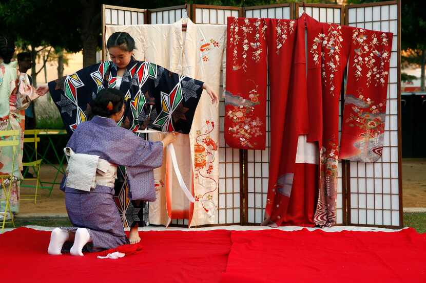 Yuki Takamatsu (standing) is dressed in a kimono by Sumiko Hashimoto during a demonstration...