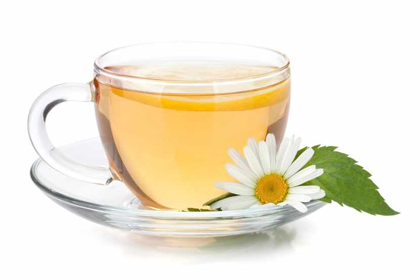 Cup of tea with lemon slice, mint leaves and chamomile flower. 
