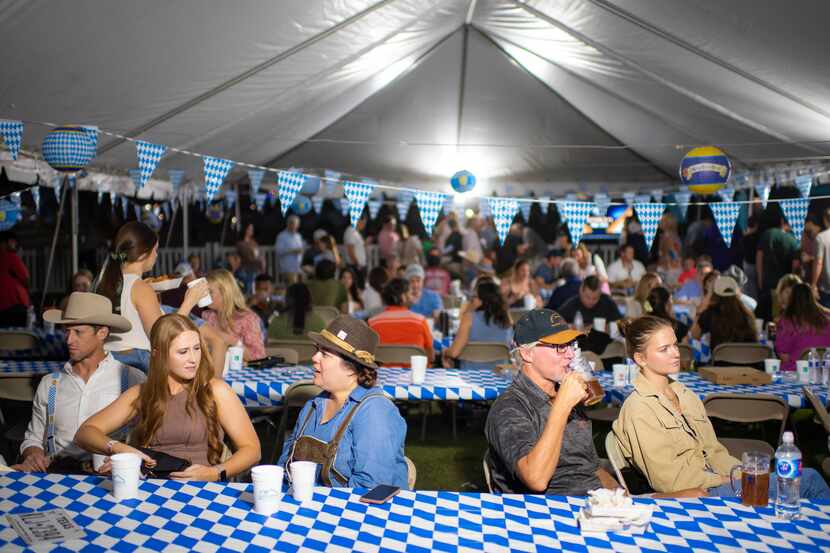 Attendees relax under a tent during the Lake Highlands Oktoberfest at Flag Pole Hill in...