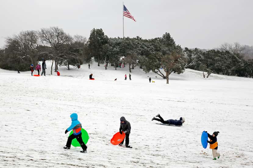 Children and adults sled along Flag Pole Hill.