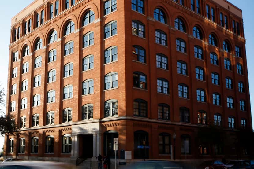 Cars drive past the Sixth Floor Museum, which was once the book depository building as...
