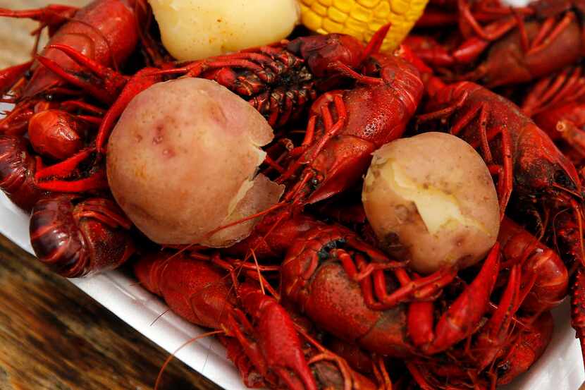 A clamshell plate of boiled crawfish, potatoes and corn sits on a table during the Frisco...