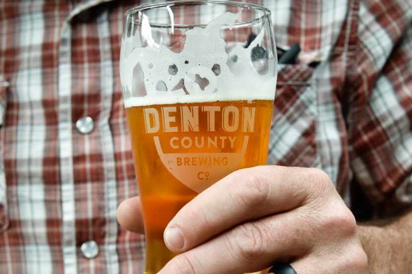 Owner Seth Morgan holds a cold beer at Denton Brewing Company. Owners are Jenny and Seth...