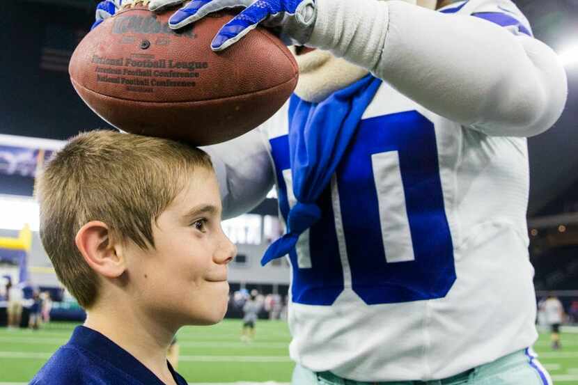 Dallas Cowboys mascot Rowdy signs a football on a boy's head  at The Star in Frisco. 