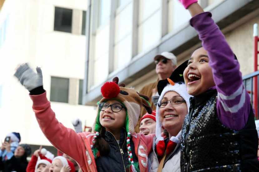 Parade goers wave to Santa at the annual Children's Health Holiday Parade through downtown...