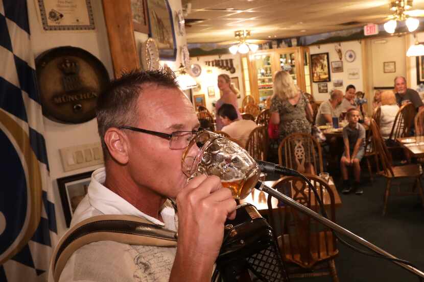 Alan Walling sips a beer as he plays traditional German music on the accordian at Bavarian...