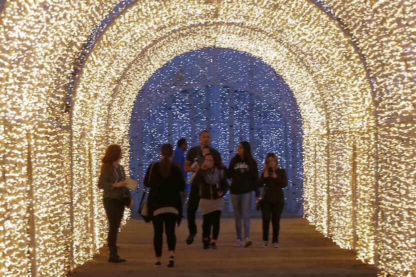 Attendees walk a tunnel of Christmas lights, part of the "Light Maze," at Enchant in Arlington.