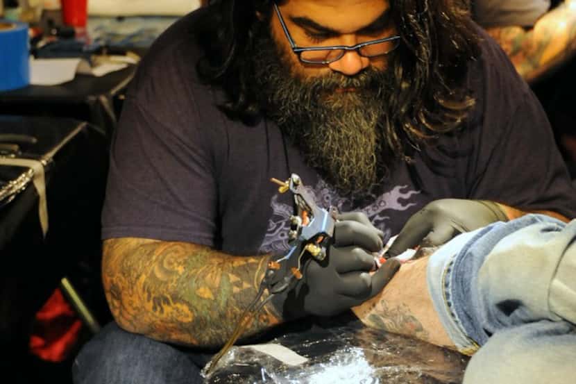 A tattoo artist is at work during the Elm Street Tattoo and Music Festival in Deep Ellum.