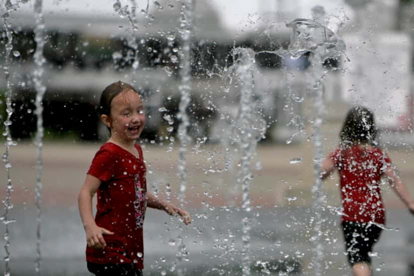 Sisters play in the spray fountains at Galatyn Park in Richardson.