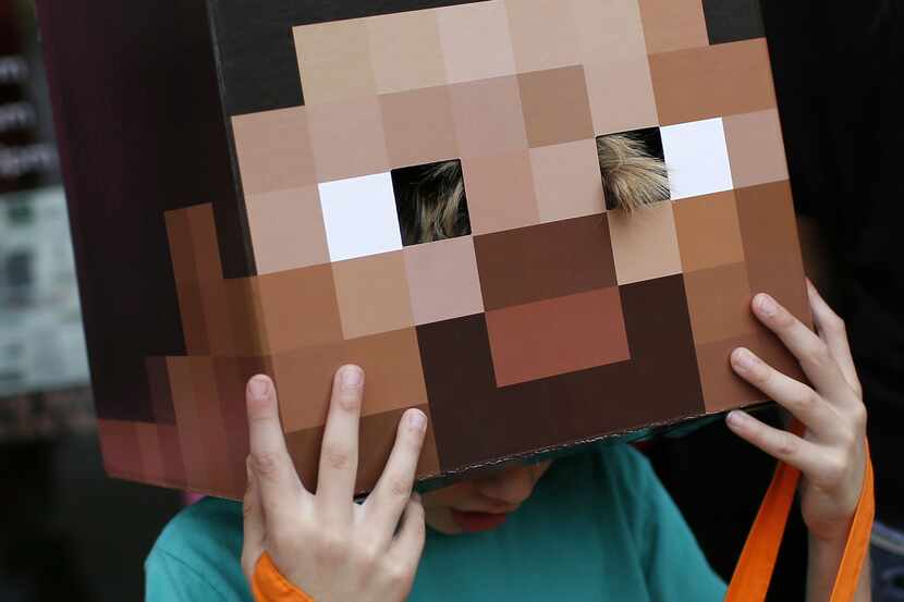 Grayson Young, 7, adjusts his "Steve from Minecraft" mask during "Trick or Treat the Square"...