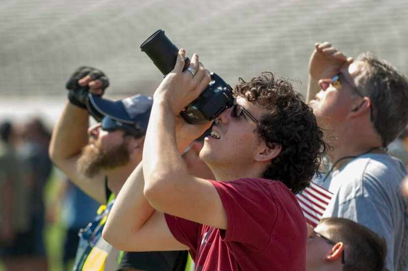 Spectators watch as members of the Red Bull Air Force parachute into the infield during the...