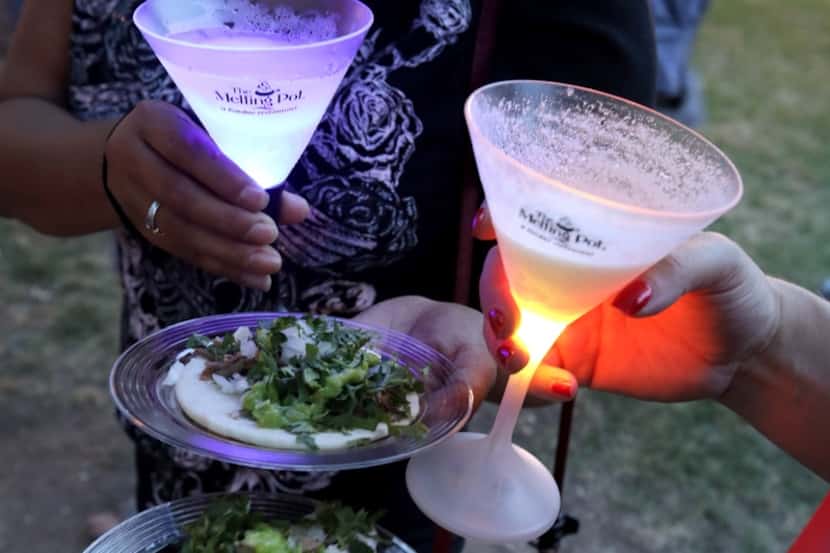 Guests at a food festival hold drinks and food samples.