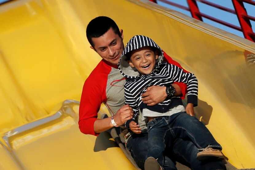 Jaime Flores and his son ride the "Super Slide" during the Main Street Festival in downtown...