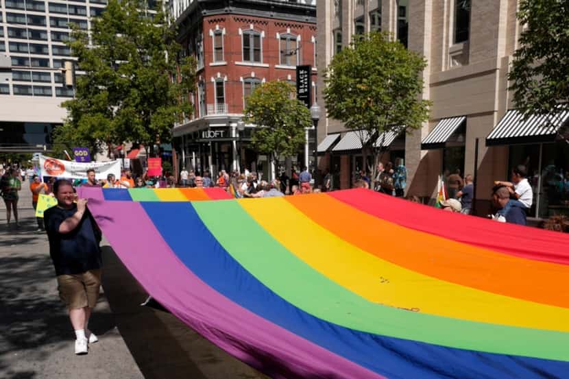 Participants in the Tarrant County Gay Pride Parade march a rainbow flag down Houston St. in...
