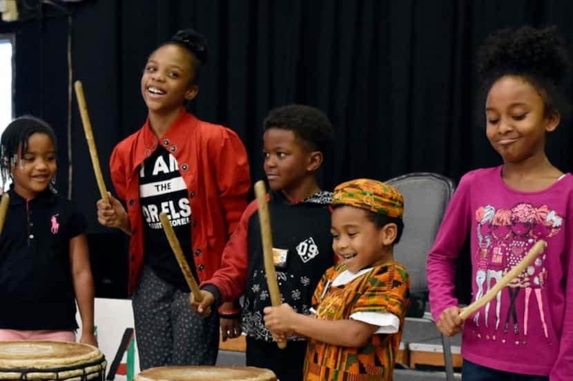 Children react with a smile while playing west African style drums.