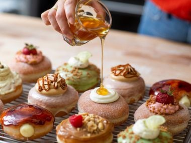 Detour Doughnuts and Coffee owner Jinny Cho tops off a cream-filled doughnut with a dollop of honey at her Frisco store..