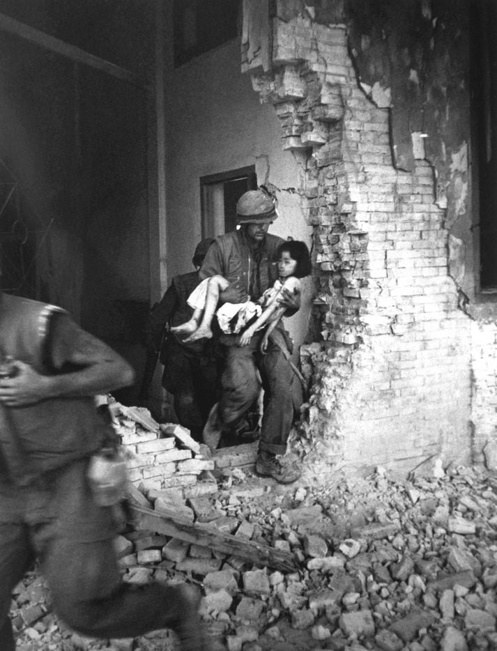A Marine carries a seriously wounded child from the ruins of a house in Hue, Vietnam, Feb....