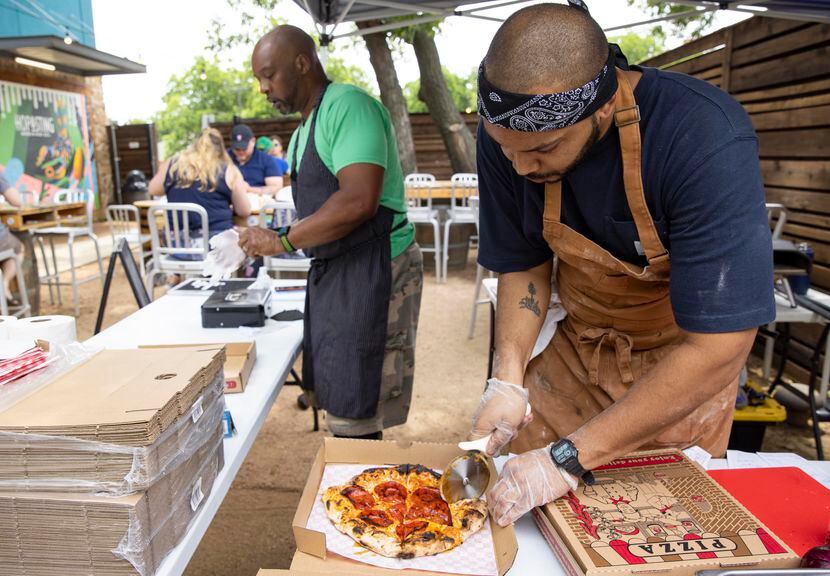 Desmon Coleman, owner of Hustle Town Pizza, boxes up a spicy pepperoni pizza while dad James...