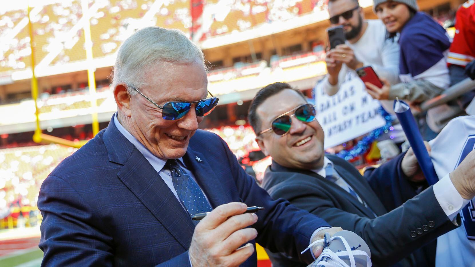 Dallas Cowboys owner Jerry Jones autographs a shoe for a fan before an NFL football game...