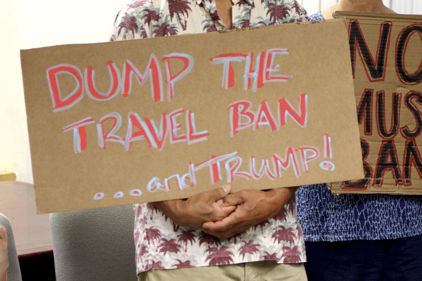 Una persona porta una pancarta en oposición a las restricciones a visas para visitantes de...