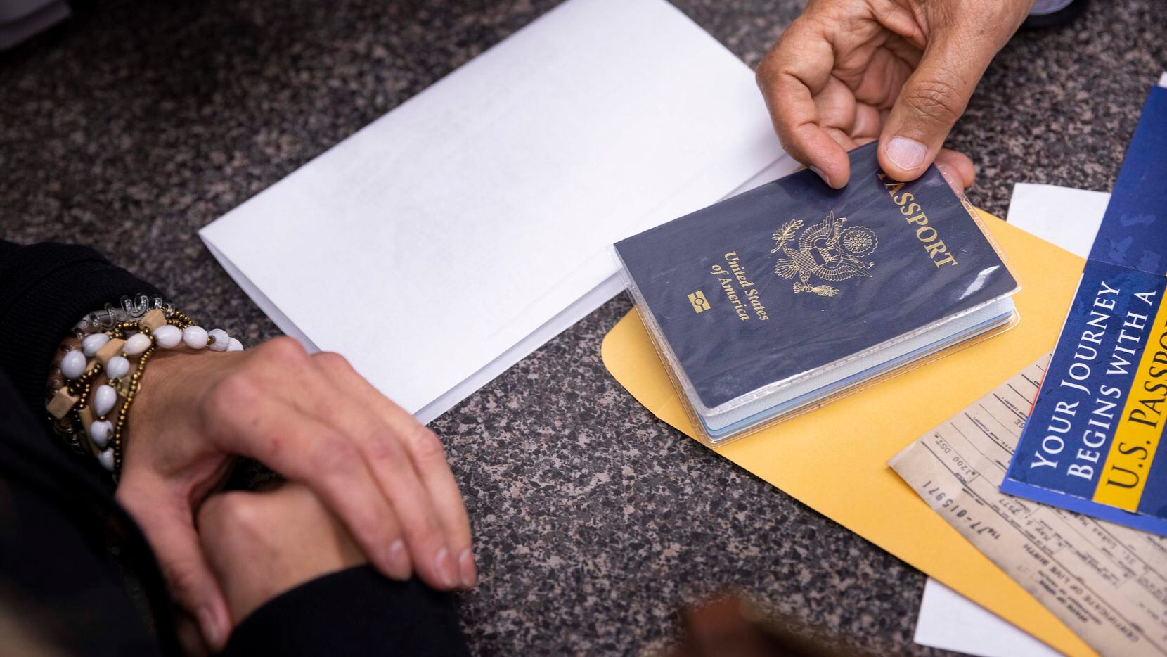 Amy Kirkland (izq.) de McKinney recibe su pasaporte antes de un viaje a Canadá en Passport...