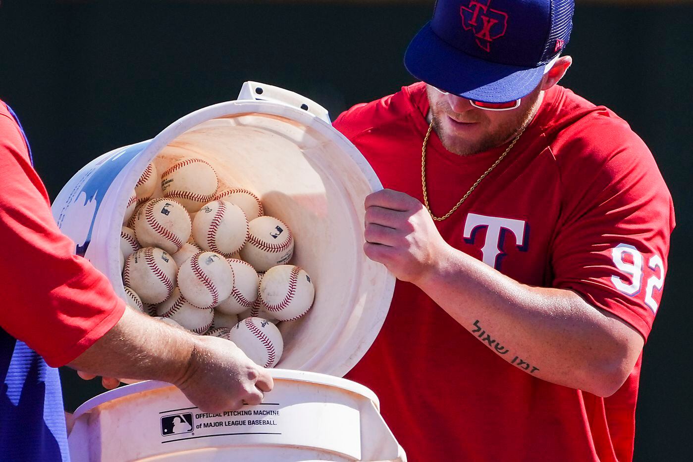 Texas Rangers infielder Blaine Crim dumps a bucket of balls while taking grounders during a...