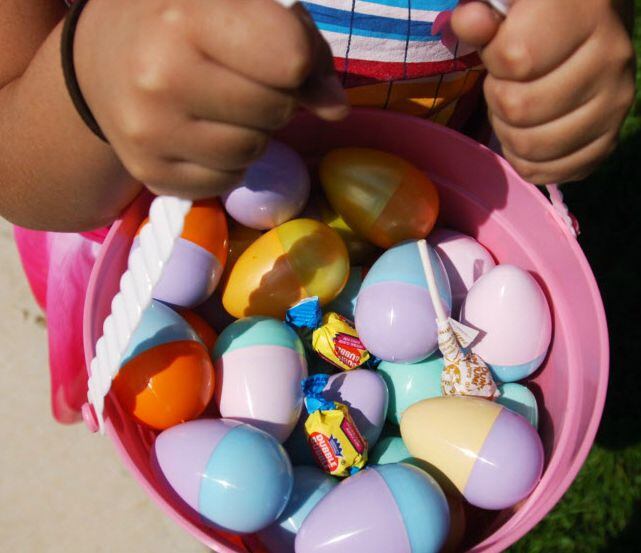 A child holds an Easter basket filled with eggs, bubble gum and suckers.