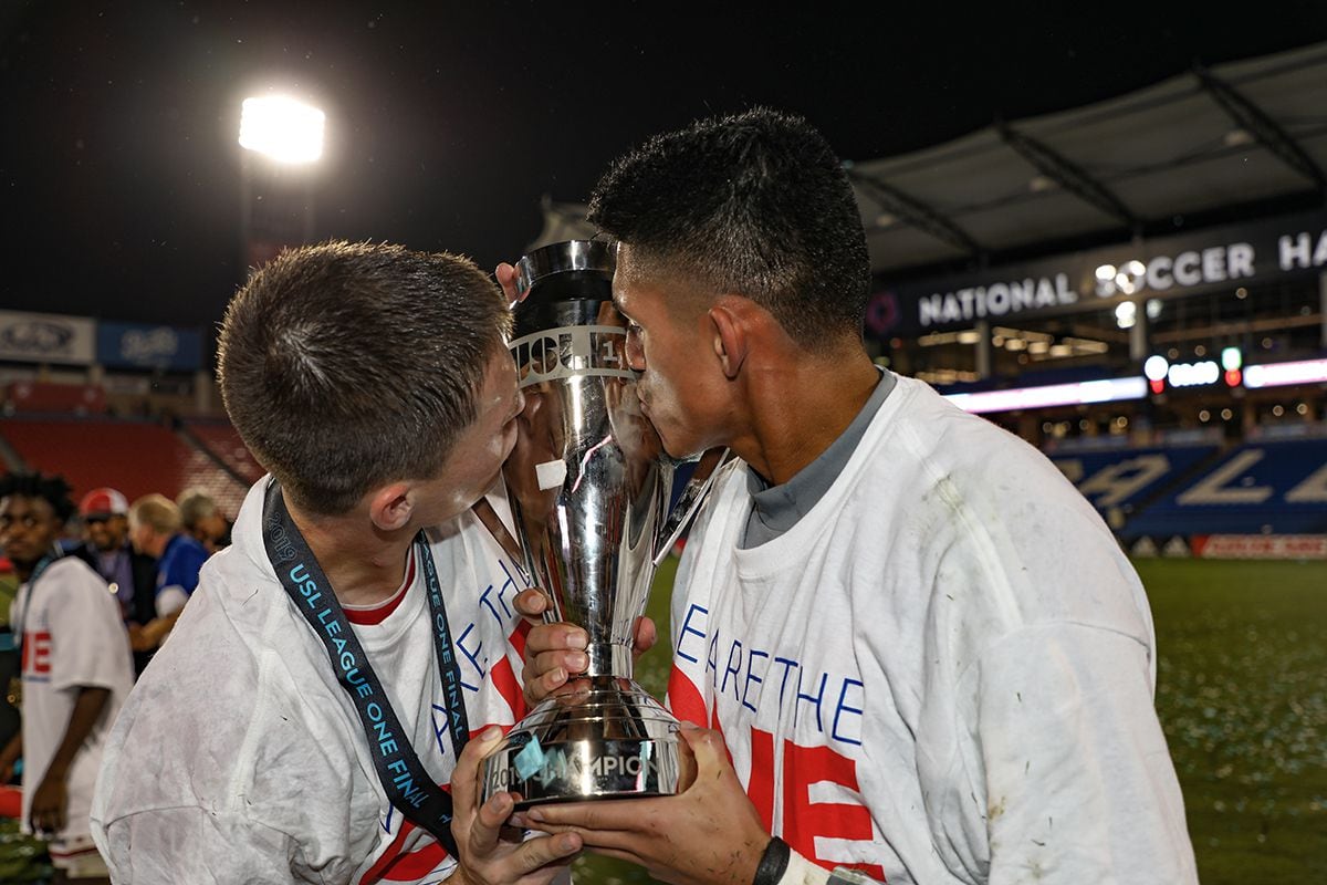 North Texas SC's Brecc Evans and Carlos Avilez kiss the USL-1 Championship trophy, October...