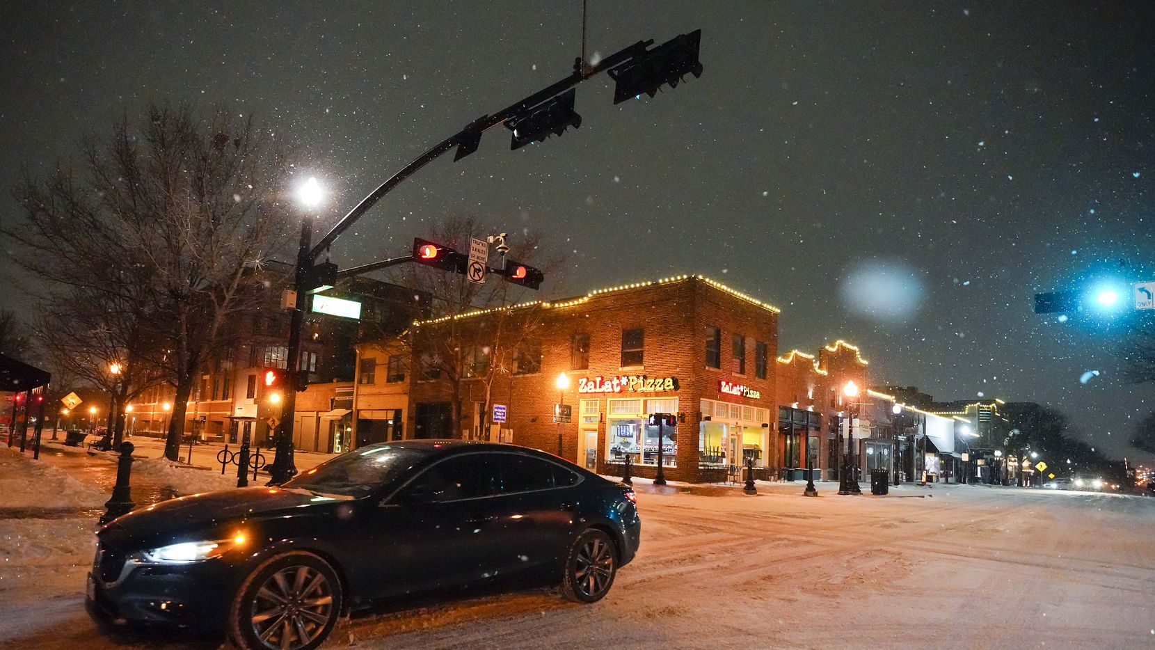 This file photo shows cars move slowly through Historic Downtown Plano as a second winter...