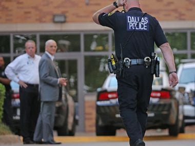 A Dallas Police officer walks to the entrance to the emergency room at Presbyterian Hospital...