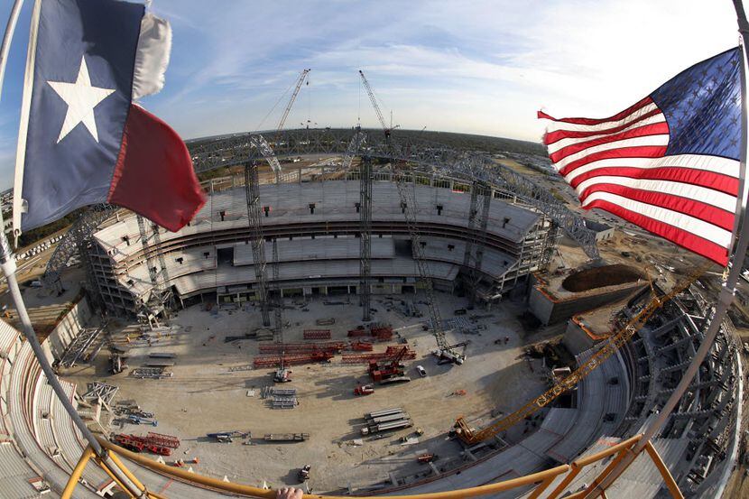 The Texas and American flags flew from the top of the tower crane at the 50 yard line of the...