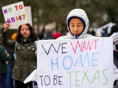 Felix, 11, and Liu Yang (background) hold signs in opposition to Texas Senate Bill 147...